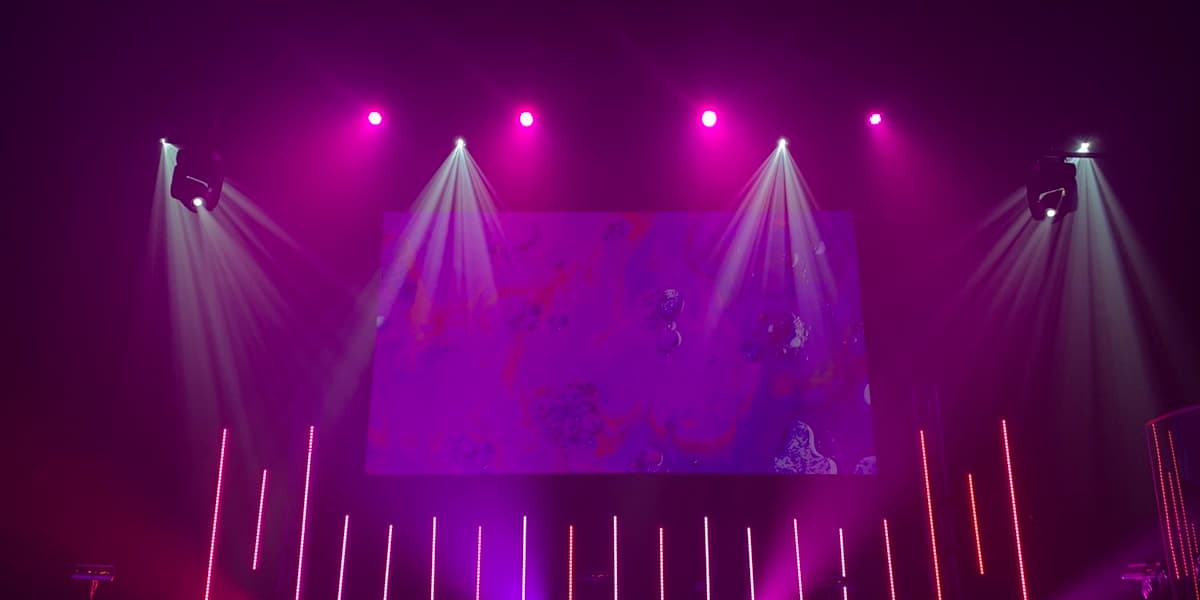 An empty stage bathed in purple and magenta light, set and ready for a show before doors