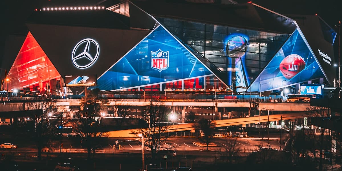 Mercedes-Benz Stadium lit up against the Atlanta skyline at dusk